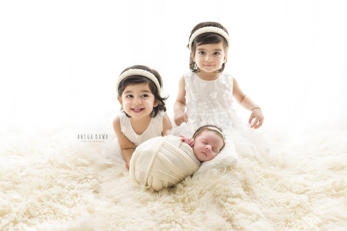 Newborn Photoshoot in Delhi: White Wrap with Siblings on White Backdrop. Photographer: Anega Bawa, Gurgaon Noida.