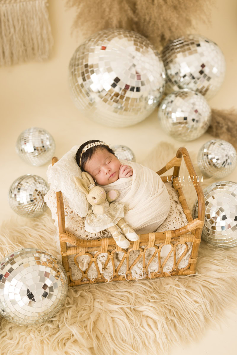 Newborn Photoshoot in Delhi: White Wrap with Soft Toy and Disco Ball on Beige Rug. Photographer: Anega Bawa, Gurgaon Noida.