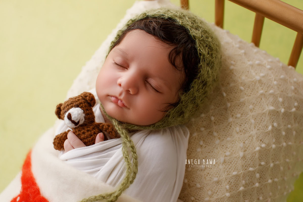 Newborn Photoshoot in Delhi: White Wrap with Soft Toy, Green Cap, Sleeping Pose. Photographer: Anega Bawa, Gurgaon Noida.