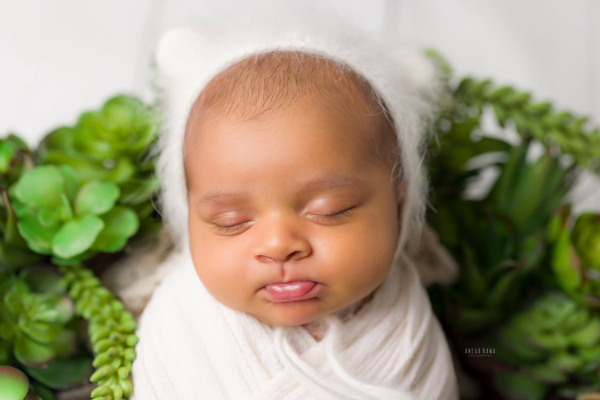 Newborn Photoshoot in Delhi: White Wrap with White Cap, Capturing a Cute Sleeping Pose. Photographer: Anega Bawa, Gurgaon Noida.