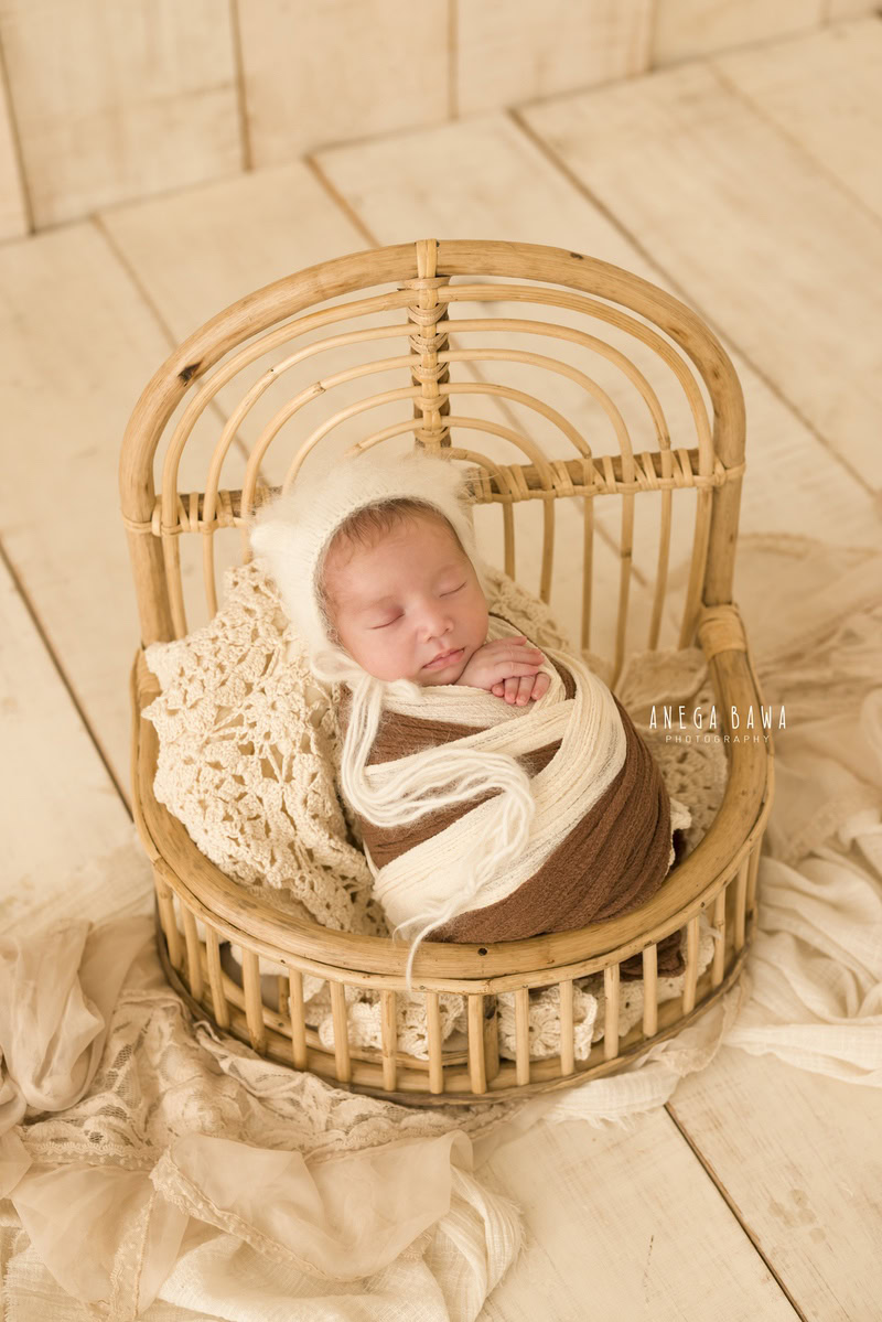 Newborn Photoshoot in Delhi: Wooden Chair with Brown and White Wrap on Beige Backdrop. Photographer: Anega Bawa, Gurgaon Noida.