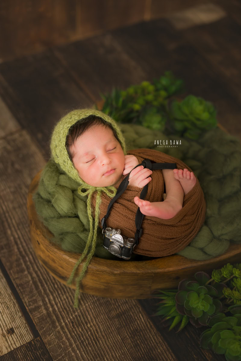 Newborn Photoshoot in Gurgaon: Brown Wrap with Green Cap Against Brown Backdrop. Photographer: Anega Bawa, Delhi Noida.