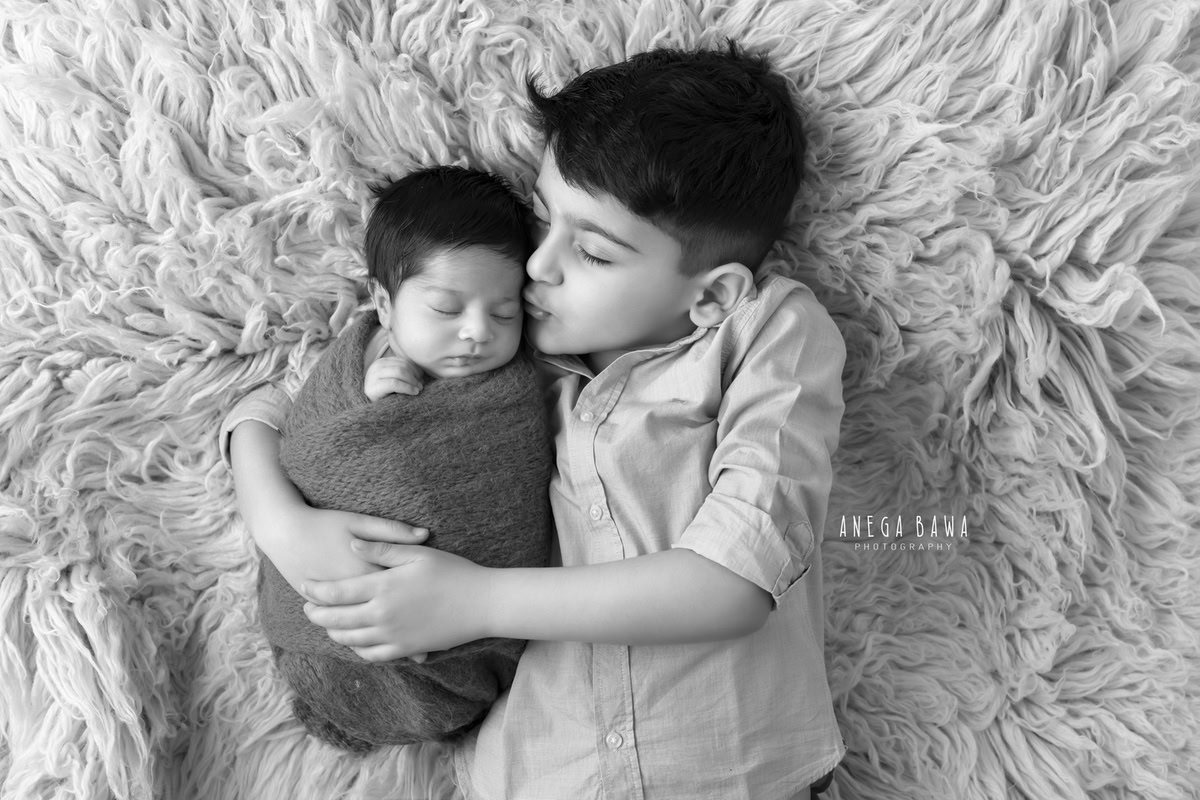 Newborn Photoshoot in Gurgaon: Brown Wrap with Grey Rug, featuring Sibling. Photographer: Anega Bawa, Delhi Noida.