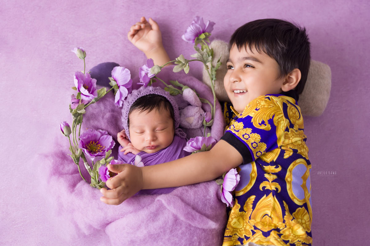 Newborn Photoshoot in Gurgaon: Lavender Wrap with Sibling Hug Pose, set against a Lavender Backdrop. Photographer: Anega Bawa, Delhi Noida.