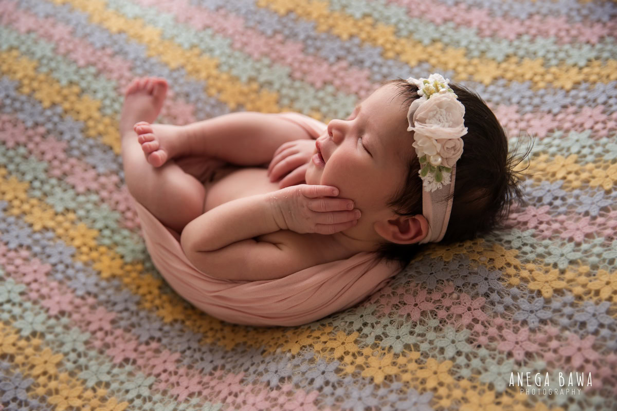 Newborn Photoshoot in Gurgaon: Multicolored Baby Sheet, Adorable Headband, Sweet Sleeping Pose. Photographer: Anega Bawa, Delhi Noida.