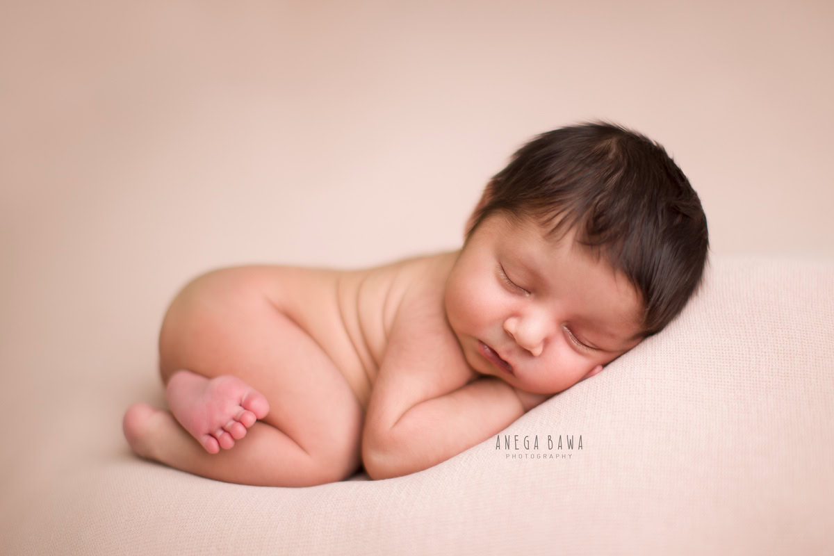 Newborn Photoshoot in Gurgaon: Sleeping baby posed against a white backdrop. Photographer: Anega Bawa Photography, Delhi Noida.