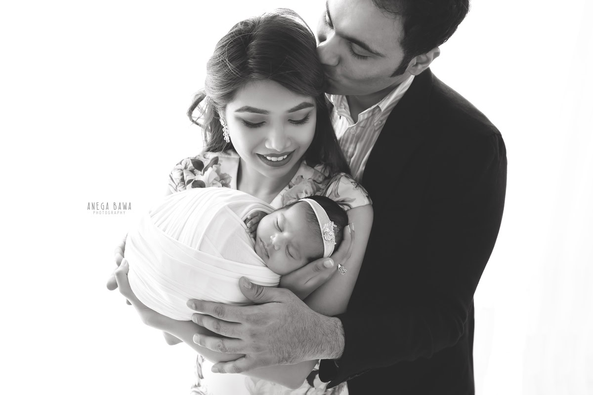 Newborn Photoshoot in Gurgaon: Family wrapped in white with a white backdrop. Photographer: Anega Bawa Photography, Delhi.