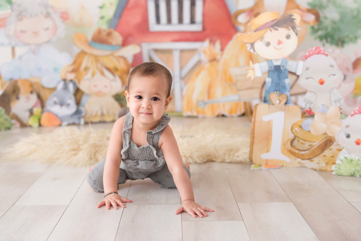 Witness the adventurous spirit of your one-year-old with a delightful crawling session on a cozy beige rug. Set against a playful cartoon backdrop, Anega Bawa Photography captures the essence of childhood in this charming sitter photoshoot in Delhi and Gurgaon.