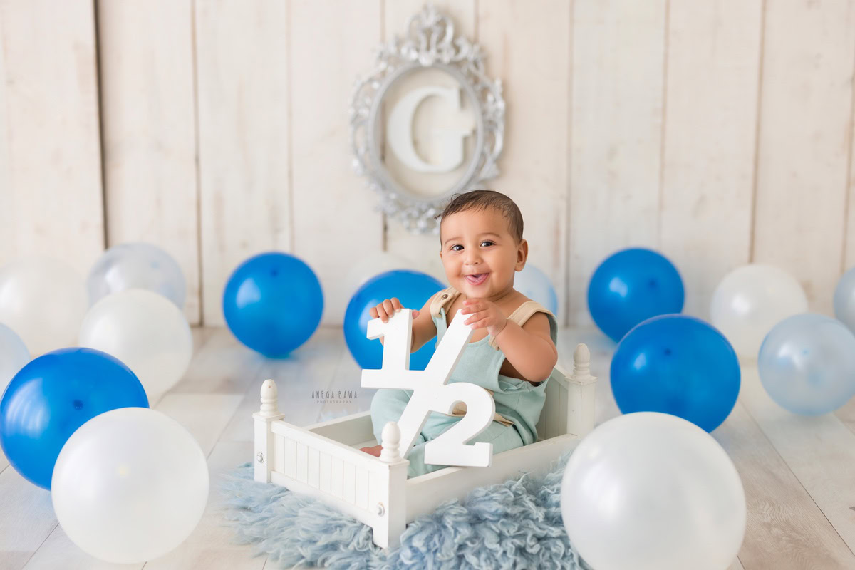 Immerse yourself in the innocence and charm of your little prince with a captivating sitter photography session in Delhi and Gurgaon by Anega Bawa Photography. Picture your six-month-old bundle of joy seated in a pristine white cot, framed by a gleaming silver frame on the wall. Surrounding him are whimsical balloons, adding a touch of playfulness to the scene, all against a serene white backdrop. Let Anega Bawa Photography freeze these precious moments in time, capturing the purity and joy of your little one's early days. Trust us to create cherished memories that you'll treasure for years to come.