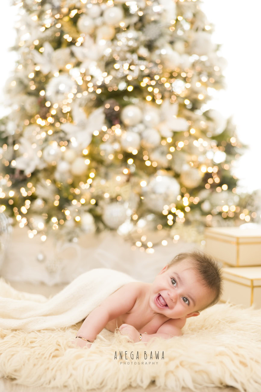 Capture the joy of the holiday season with your 3, 4, 5, or 6-month-old baby boy on a beige rug beside a Christmas tree adorned with golden lights. Contact Anega Bawa for this heartwarming photo shoot in Delhi, Gurgaon, or Noida.