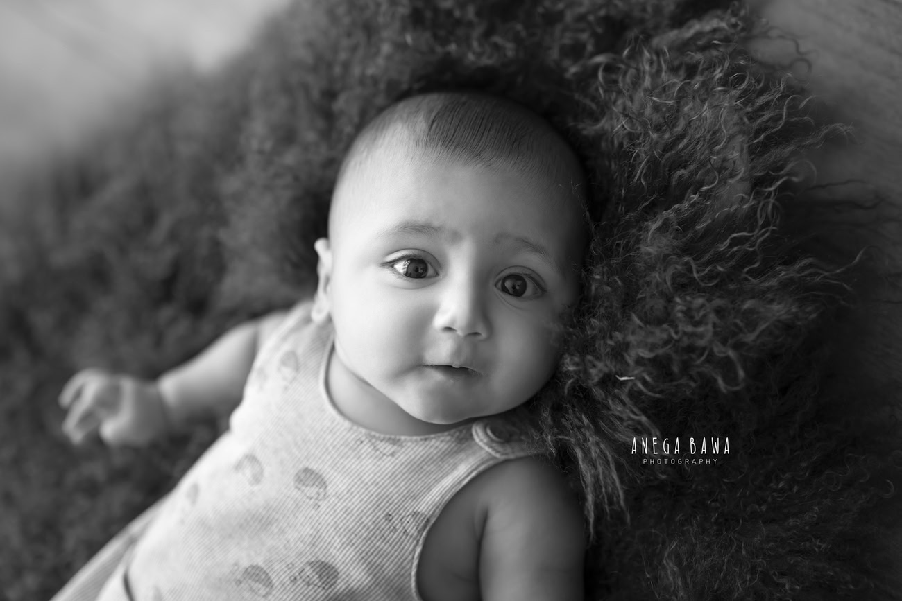 Capture the playful spirit of your 3, 4, 5, or 6-month-old baby boy on a vibrant green rug, depicted in timeless black and white. Contact Anega Bawa for your baby boy's photoshoot in Delhi, Gurgaon, or Noida.