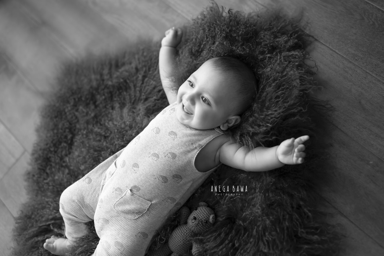 Capture the playful spirit of your 3, 4, 5, or 6-month-old baby boy on a vibrant green rug, depicted in timeless black and white. Contact Anega Bawa for your baby boy's photoshoot in Delhi, Gurgaon, or Noida.