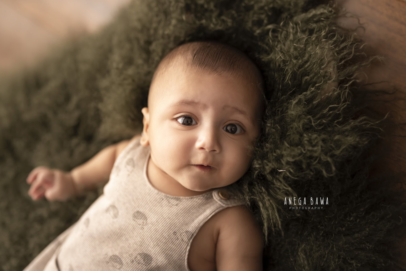 Immerse your 3, 4, 5, or 6-month-old baby boy in a natural ambiance with a lush green rug against a warm brown backdrop. Book a session with Anega Bawa for a memorable baby boy photoshoot in Delhi, Gurgaon, or Noida.