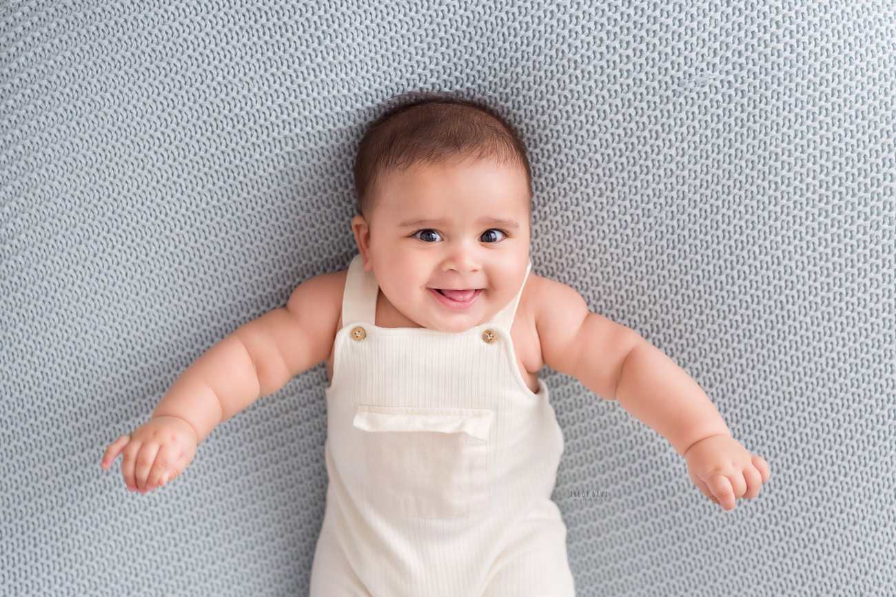 Baby boy photo shoot, 6, 5, 3, or 4 months, white baby boysuit, grey backdrop. Location: Delhi, Gurgaon, Noida. Photographer: Anega Bawa.