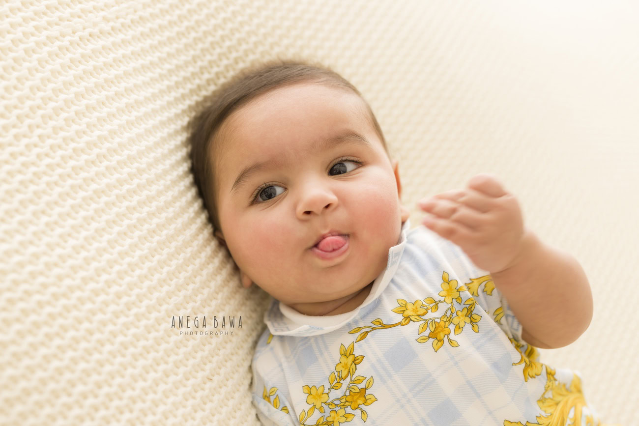 Baby boy photo shoot, 6, 5, 3, or 4 months, white backdrop, cute tongue pose. Location: Delhi, Gurgaon, Noida. Photographer: Anega Bawa.