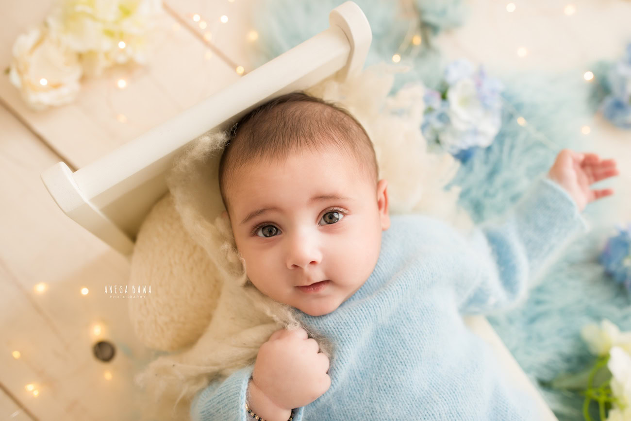 Dress your little prince in a charming blue baby boysuit for his photoshoot. Against a neutral beige backdrop, every precious moment will be beautifully captured. Reach out to Anega Bawa for baby photography in Delhi, Gurgaon, or Noida.