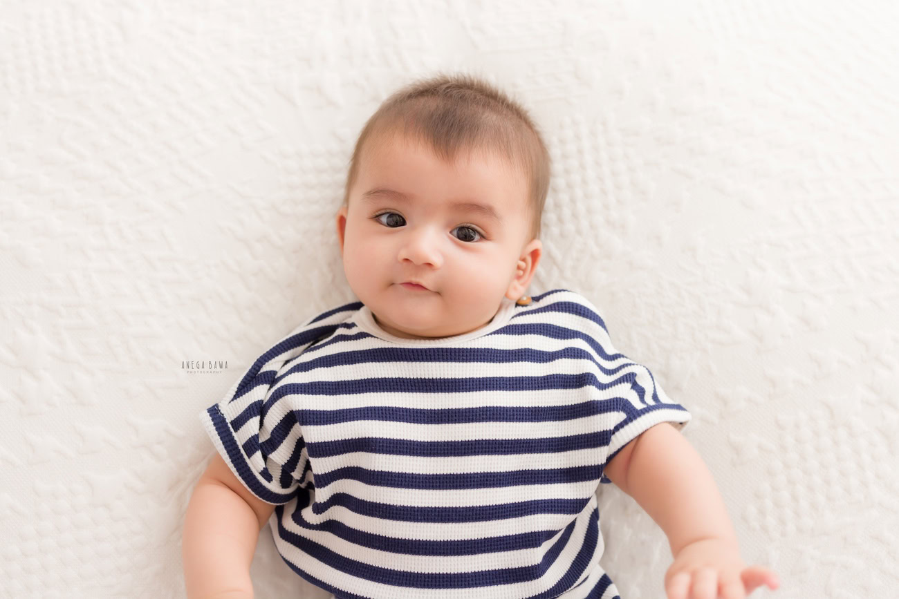 Baby boy photographer, 6 or 4 or 3 or 5 months, white backdrop, blue stripes baby boy suit. Location: Delhi, Gurgaon, Noida. Photographer: Anega Bawa.