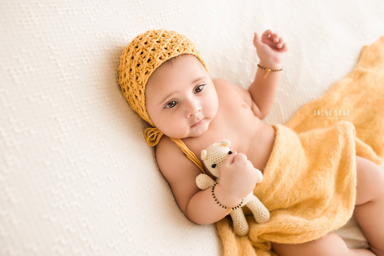 Create lasting memories of your 6, 4, 3, or 5-month-old baby boy in a charming yellow wrap and matching cap, set against a pristine white backdrop. Book your photoshoot with Anega Bawa in Delhi, Gurgaon, or Noida.