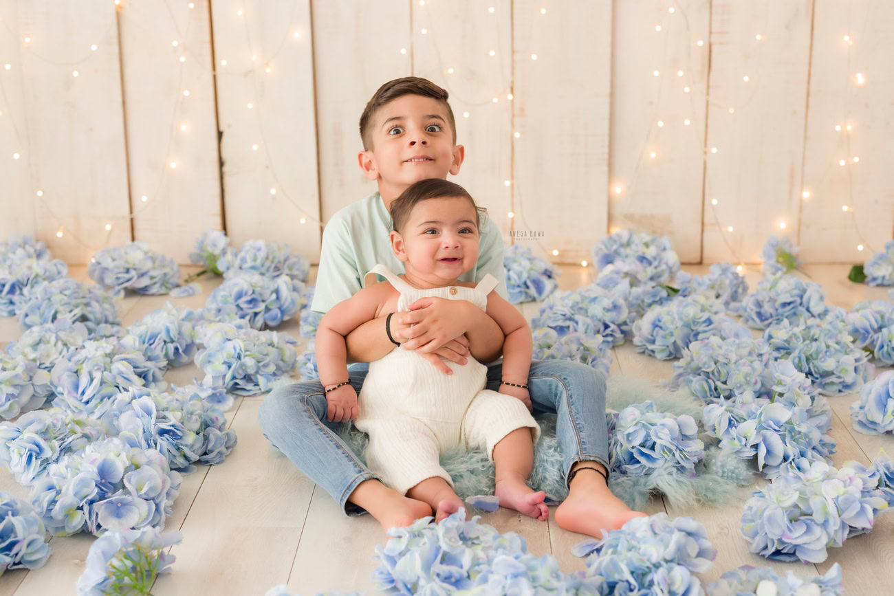 Baby boy photography, 5 or 4 or 3 or 6 months, beige backdrop, blue flowers, sibling. Location: Delhi, Gurgaon, Noida. Photographer: Anega Bawa.