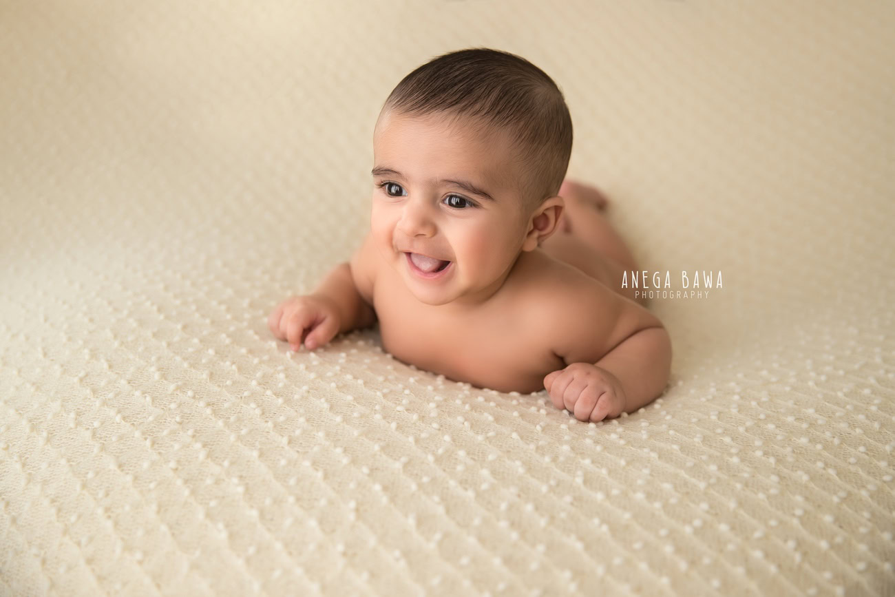 Captivating baby boy photography session featuring the adorable smiles of a 5, 4, 3, 6-month-old against a warm beige backdrop. Expertly captured by Anega Bawa, the esteemed baby photographer in Delhi, Gurgaon, and Noida.