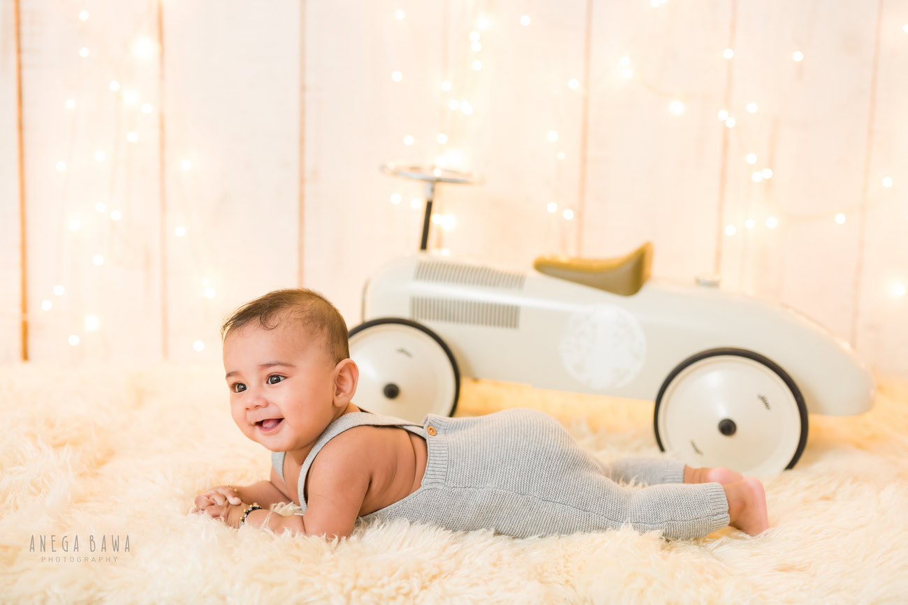 Baby boy photography, 5 or 4 or 3 or 6 months, beige rug, beige backdrop, golden lights, cute lying pose. Location: Delhi, Gurgaon, Noida. Photographer: Anega Bawa.