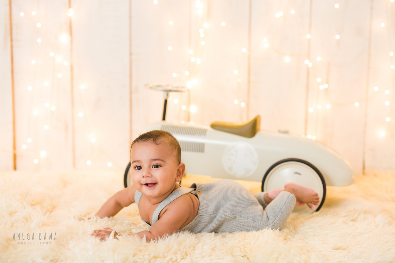 Baby boy photography, 5 or 4 or 3 or 6 months, beige rug, beige backdrop, golden lights, lying down pose. Location: Delhi, Gurgaon, Noida. Photographer: Anega Bawa.