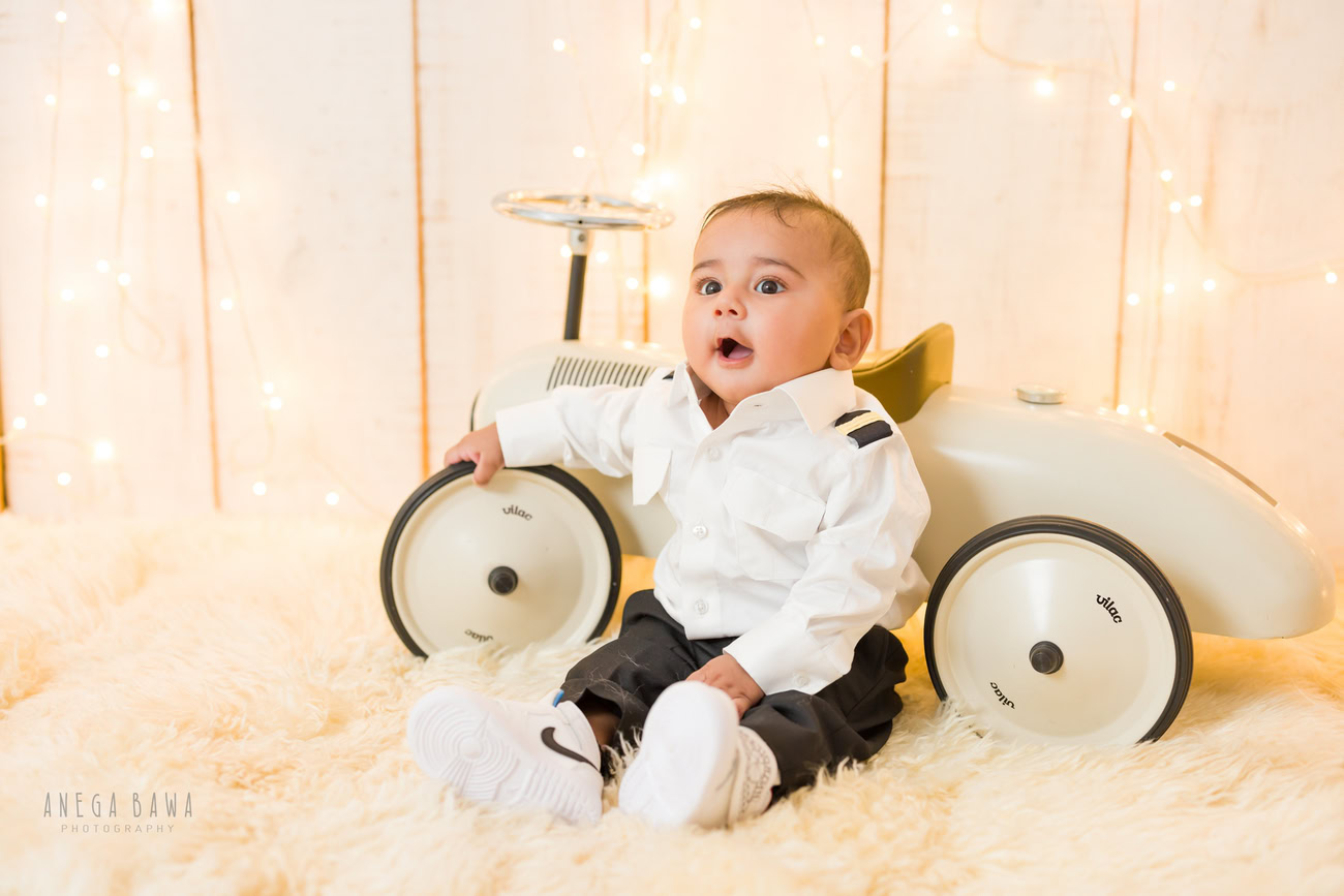 Baby boy photography, 5 or 4 or 3 or 6 months, beige rug, beige backdrop, toy car, formal dress. Location: Delhi, Gurgaon, Noida. Photographer: Anega Bawa.
