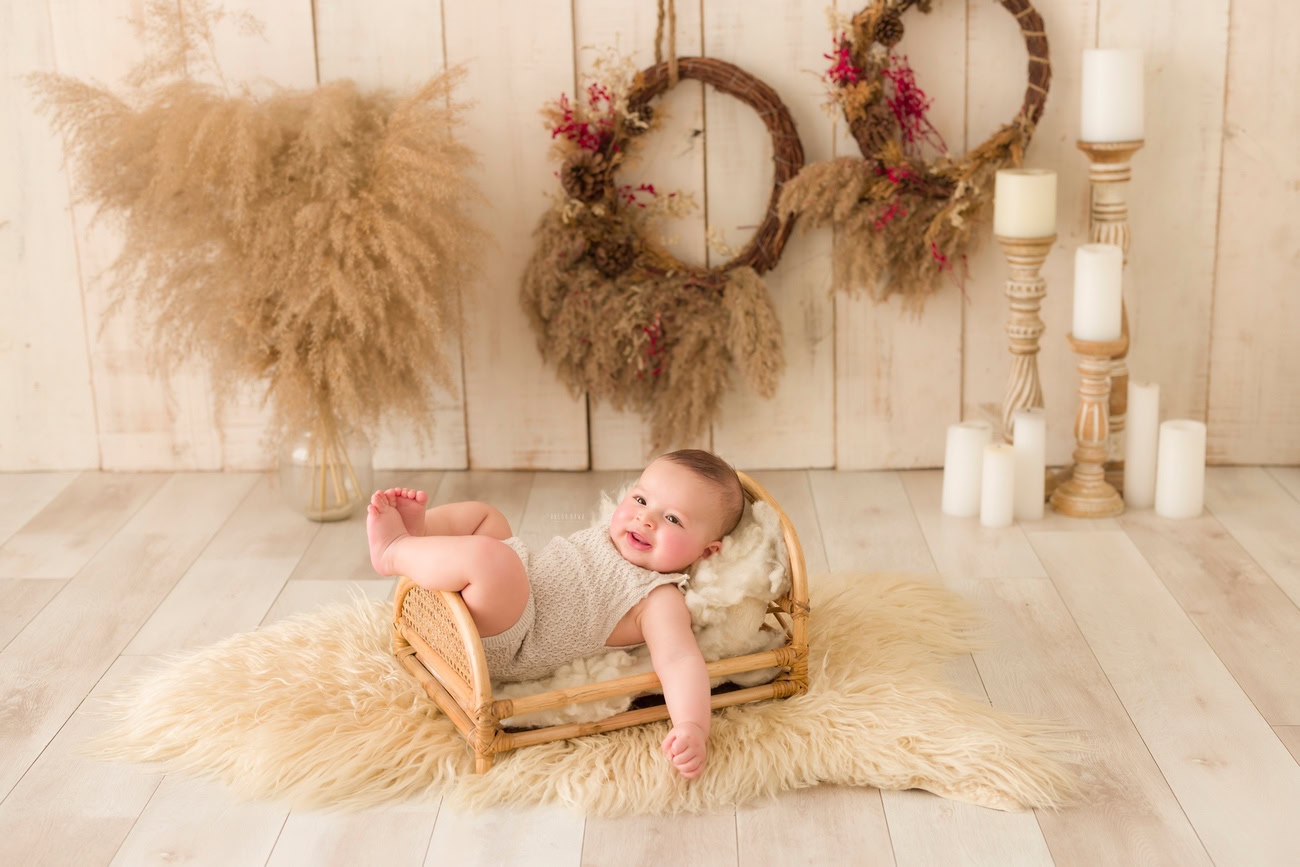 Baby boy photography, 5, 4, 3, or 6 months, beige rug, wooden frame, shrubs, candles, beige backdrop. Location: Delhi, Gurgaon, Noida. Photographer: Anega Bawa.