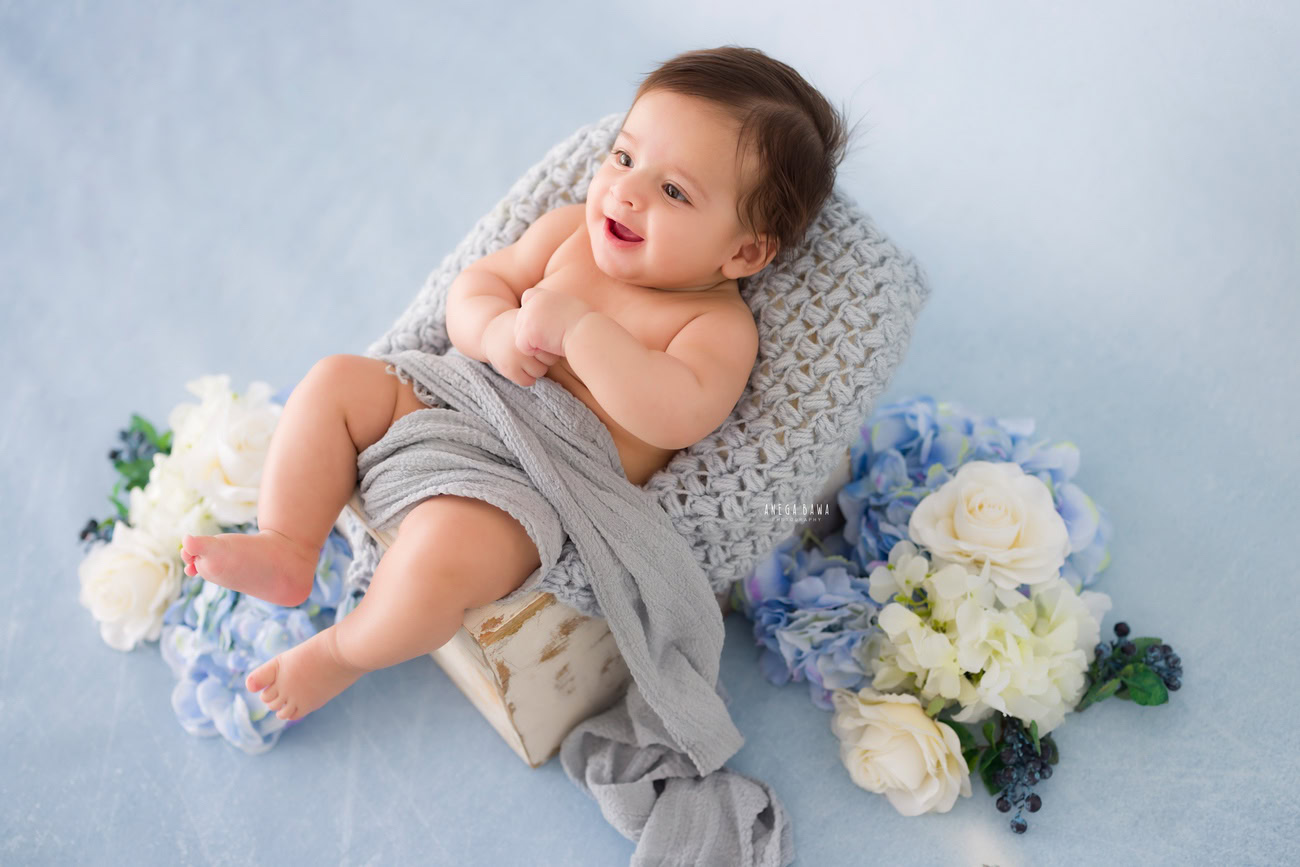 Baby boy photography, 5 or 4 or 3 or 6 months, blue backdrop, blue and white flowers, grey sheet. Location: Delhi, Gurgaon, Noida. Photographer: Anega Bawa.