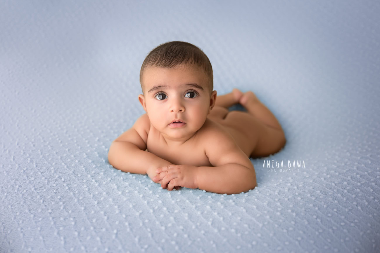 Enchanting baby boy photography session highlighting the charm of a 5, 4, 3, 6-month-old against a serene blue backdrop. Expertly crafted by Anega Bawa, the premier baby photographer in Delhi, Gurgaon, and Noida.