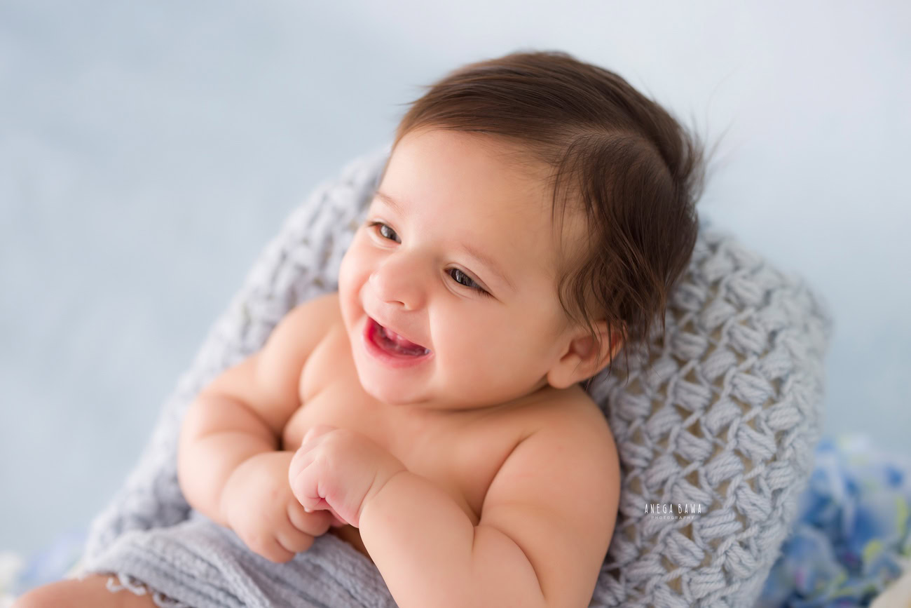 Baby boy photography, 5 or 4 or 3 or 6 months, blue backdrop, grey sheet, cute smiling pose. Location: Delhi, Gurgaon, Noida. Photographer: Anega Bawa.