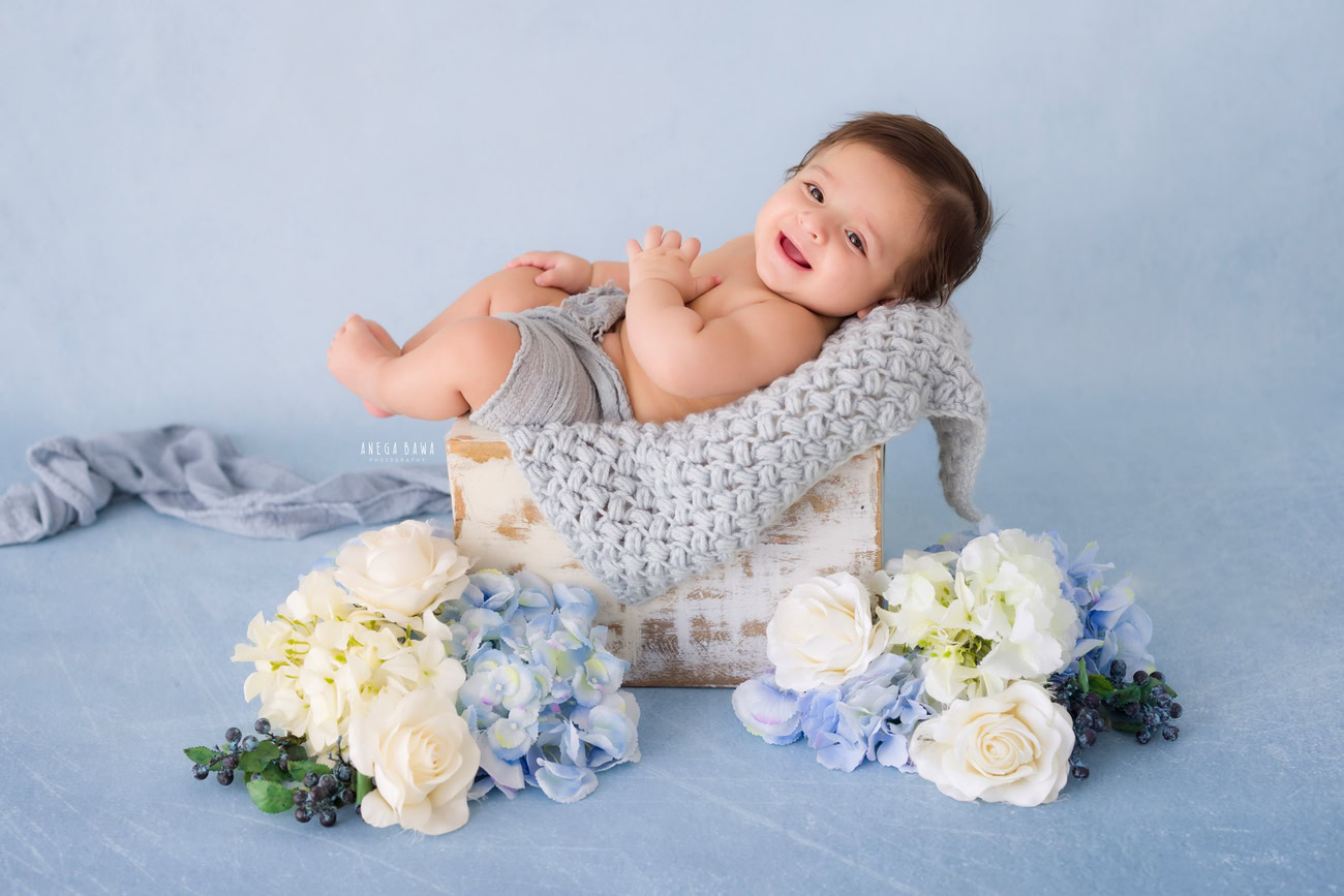 Baby boy photography, 5 or 4 or 3 or 6 months, blue backdrop, grey wrap, white and blue flowers. Location: Delhi, Gurgaon, Noida. Photographer: Anega Bawa.