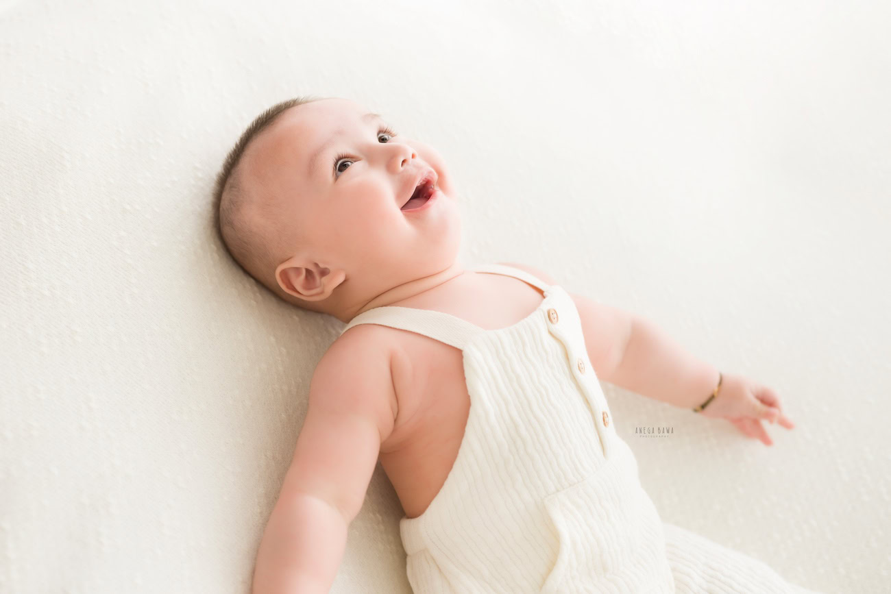 Baby boy photography, 5, 4, 3, or 6 months, white backdrop, cute laughing pose. Location: Delhi, Gurgaon, Noida. Photographer: Anega Bawa.