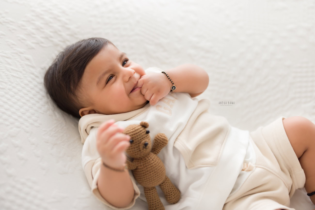 Baby boy photography, 5 or 4 or 3 or 6 months, white suit, soft toy, white backdrop. Location: Delhi, Gurgaon, Noida. Photographer: Anega Bawa.