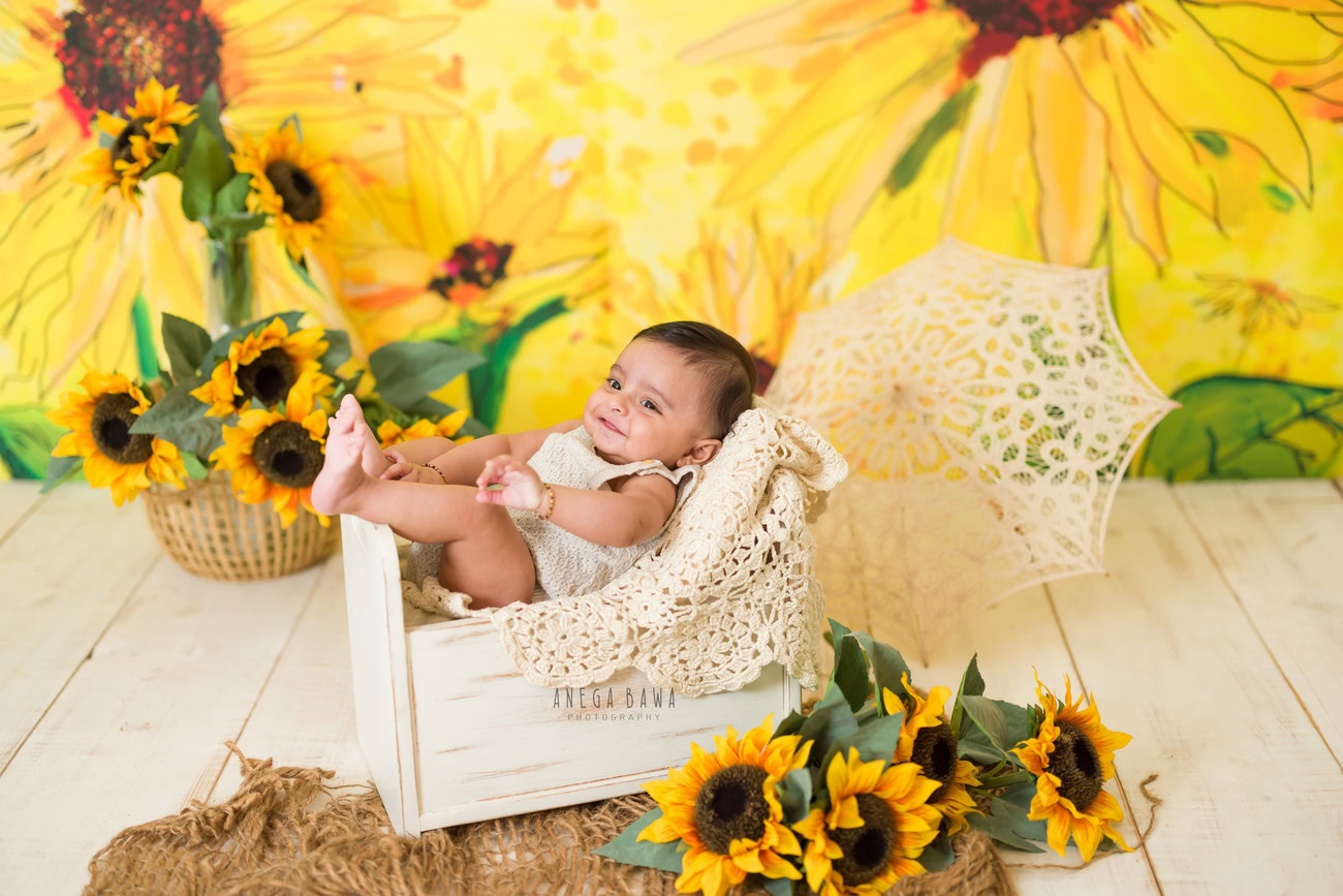 Baby boy photography, 5, 4, 3, or 6 months, white wooden cot, sunflowers backdrop, brown rug. Location: Delhi, Gurgaon, Noida. Photographer: Anega Bawa.