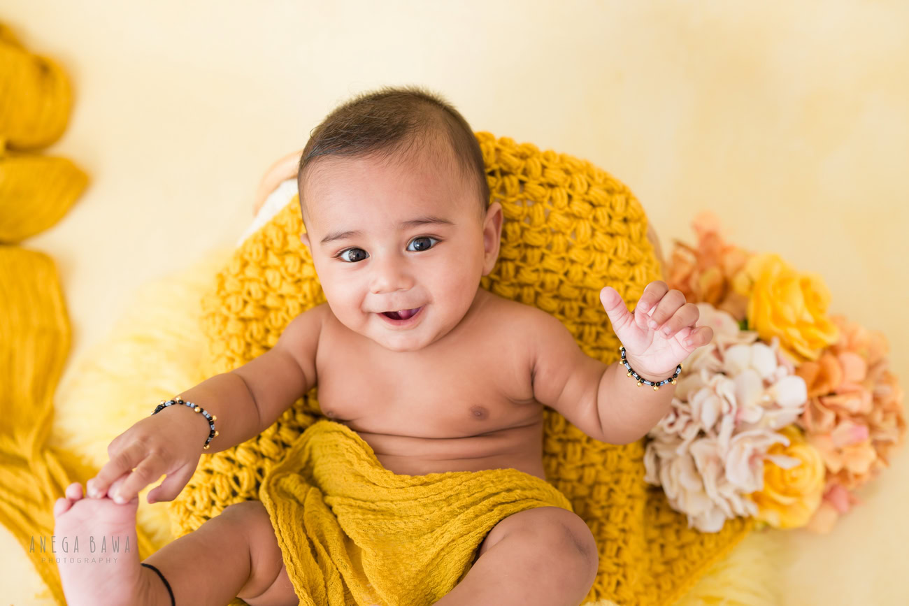 Baby boy photography, 5 or 4 or 3 or 6 months, yellow wrap, flowers, cute smiling pose. Location: Delhi, Gurgaon, Noida. Photographer: Anega Bawa.