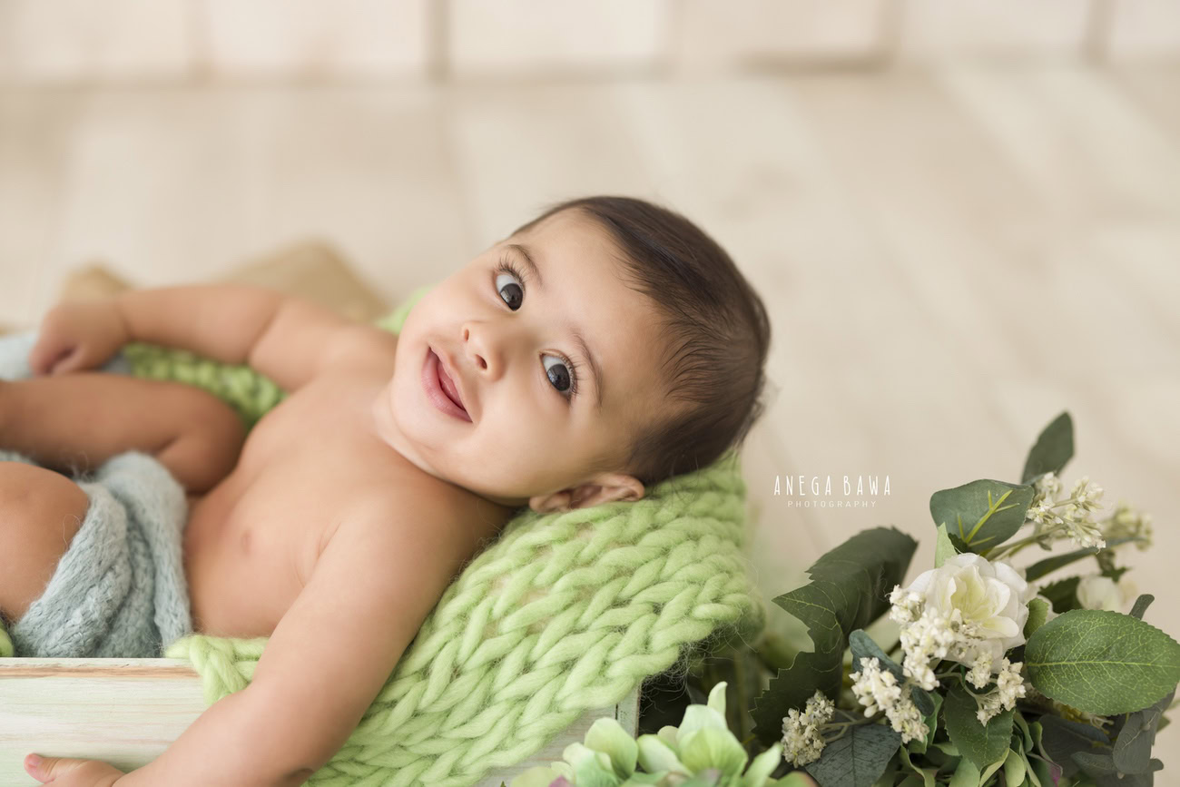 Baby boy photoshoot, 6, 5, 4, 3 months, beige backdrop, white flowers, green leaves. Location: Delhi, Gurgaon, Noida. Photographer: Anega Bawa.