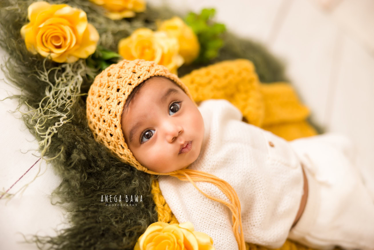 Create timeless memories of your baby boy at 3, 4, 5, or 6 months with a cute cap amidst vibrant yellow flowers, set against a lush green rug. Book your photoshoot with Anega Bawa in Delhi, Gurgaon, or Noida.