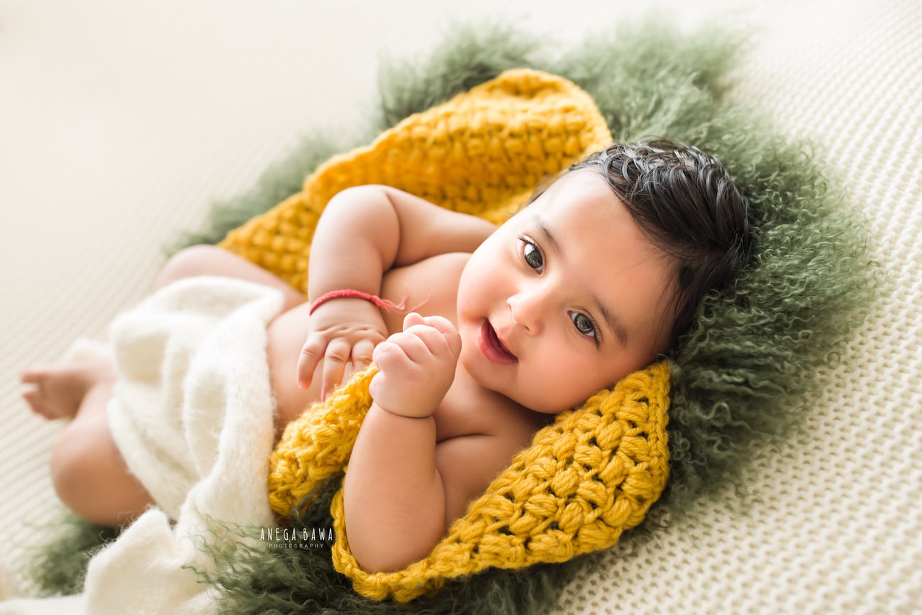 Enchanting baby boy photoshoot capturing the adorable 6, 5, 4, 3-month-old on a lush green rug, wrapped in a pristine white wrap. Crafted with expertise by Anega Bawa, the premier baby photographer in Delhi, Gurgaon, and Noida.