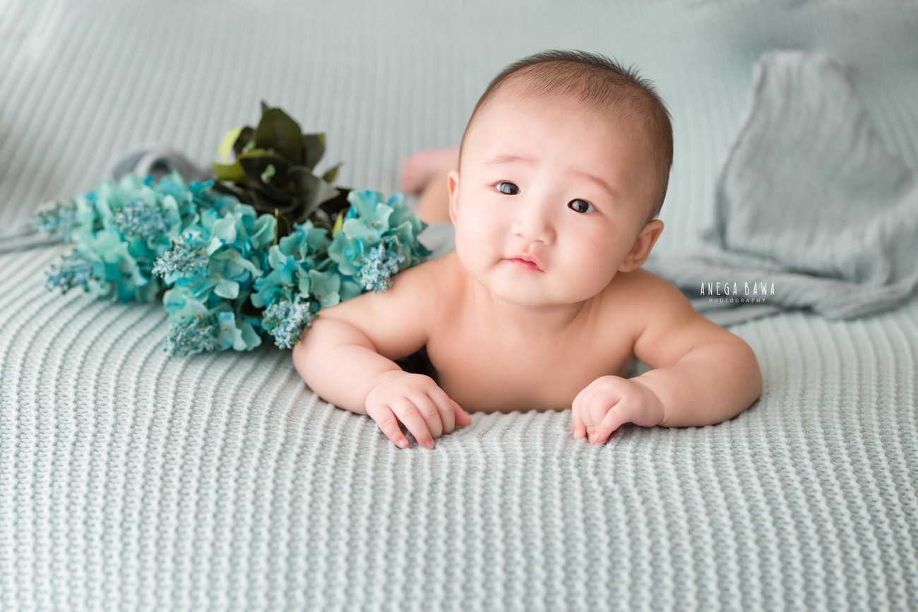 Baby boy photoshoot, 6, 5, 4, 3 months, grey backdrop, blue flowers, cute smiling pose. Location: Delhi, Gurgaon, Noida. Photographer: Anega Bawa.