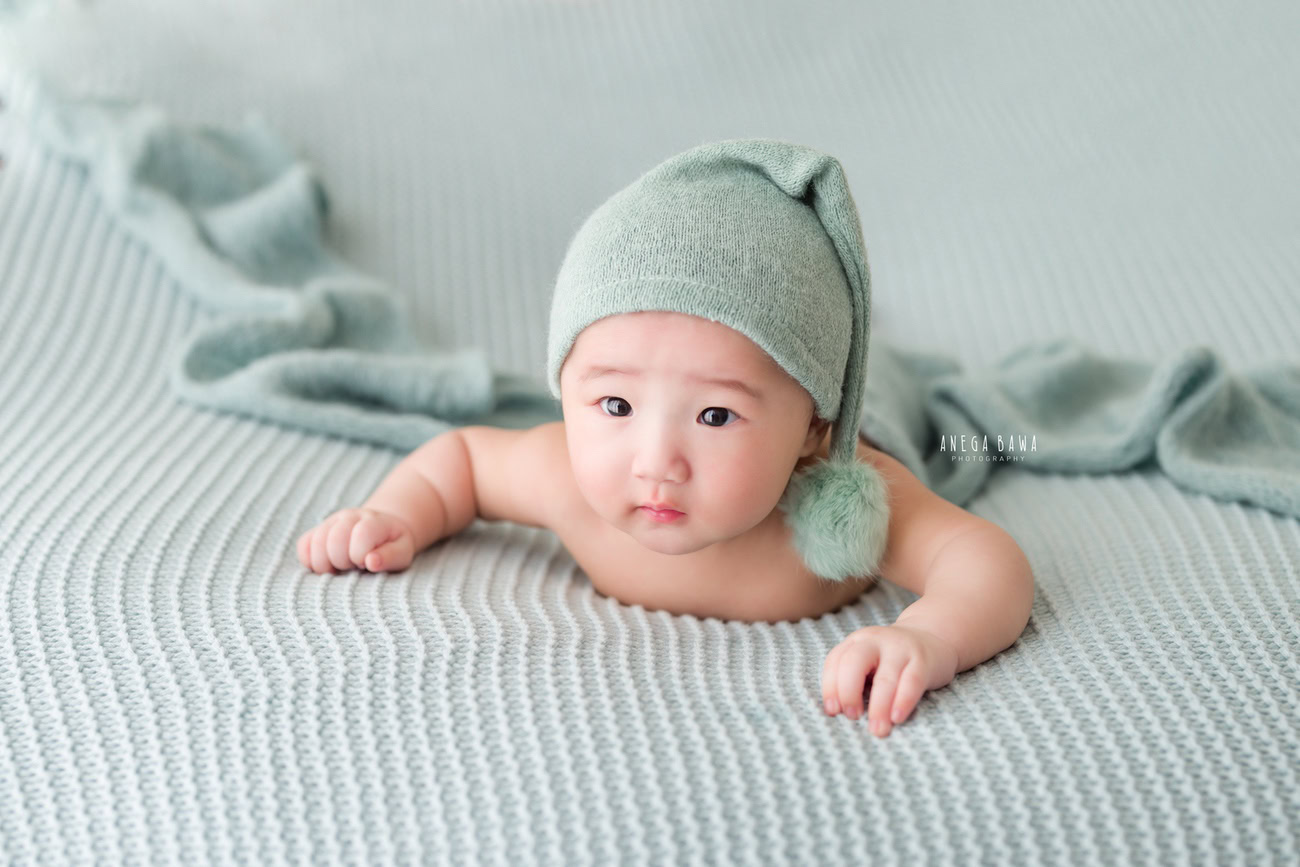 Baby boy photoshoot, 6, 5, 4, 3 months, grey backdrop, cute cap, naughty eyes. Location: Delhi, Gurgaon, Noida. Photographer: Anega Bawa.