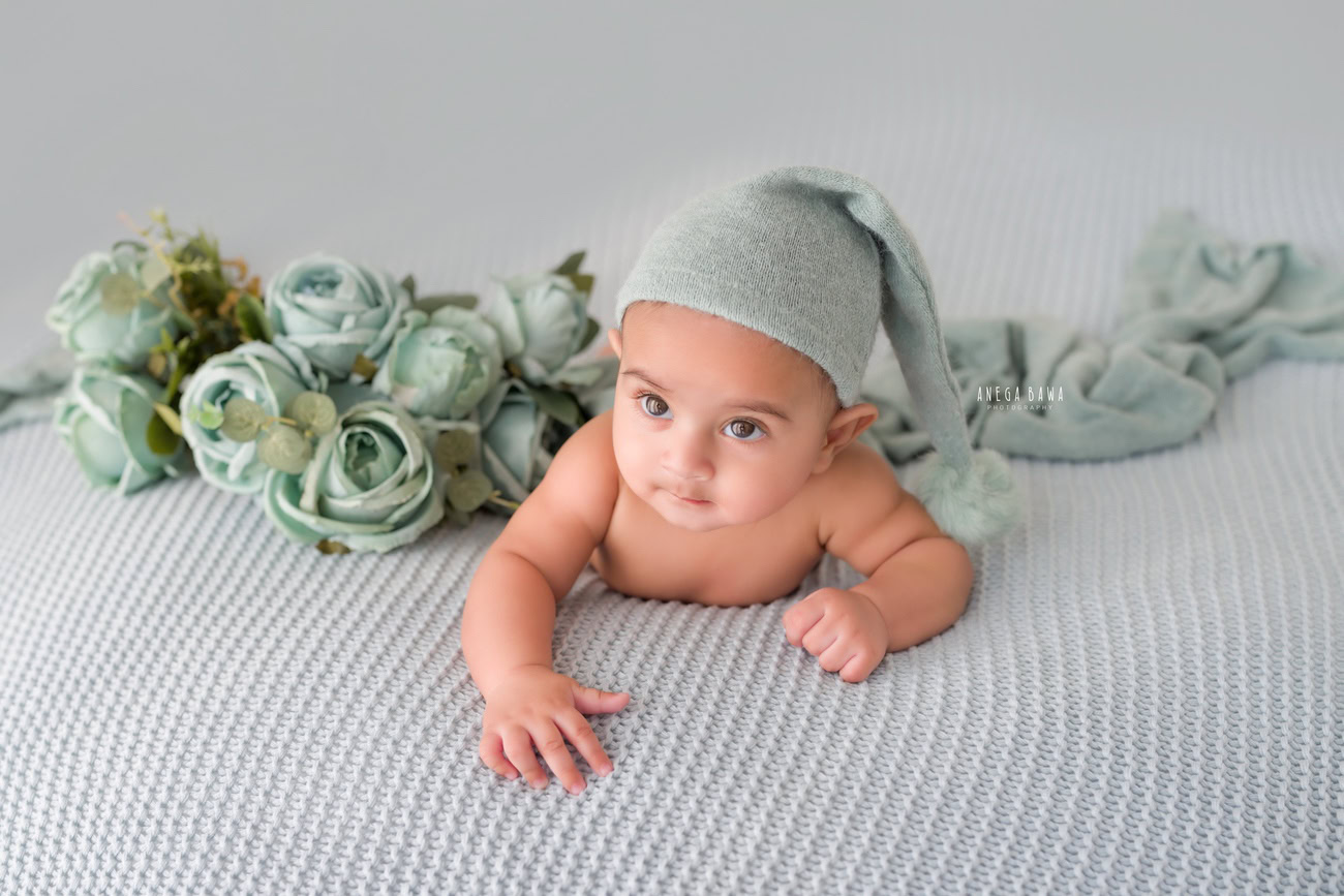 Baby boy photoshoot, 6 or 5 or 4 or 3 months, grey cap, grey backdrop, flowers. Location: Delhi, Gurgaon, Noida. Photographer: Anega Bawa.
