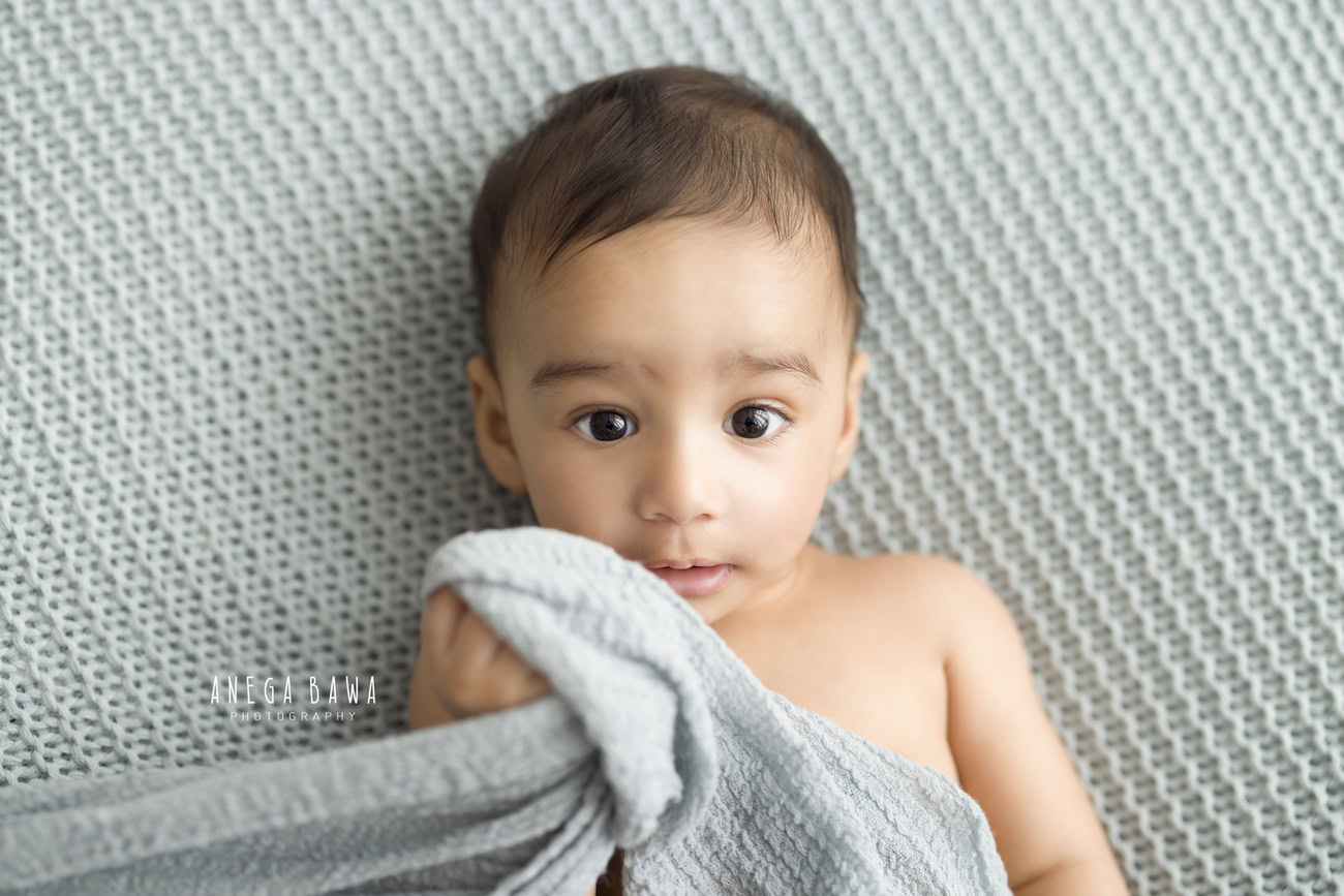 Experience the pure joy of your baby boy at 3, 4, 5, or 6 months with a grey wrap against a serene grey backdrop. Trust Anega Bawa for capturing these precious moments in Delhi, Gurgaon, or Noida.