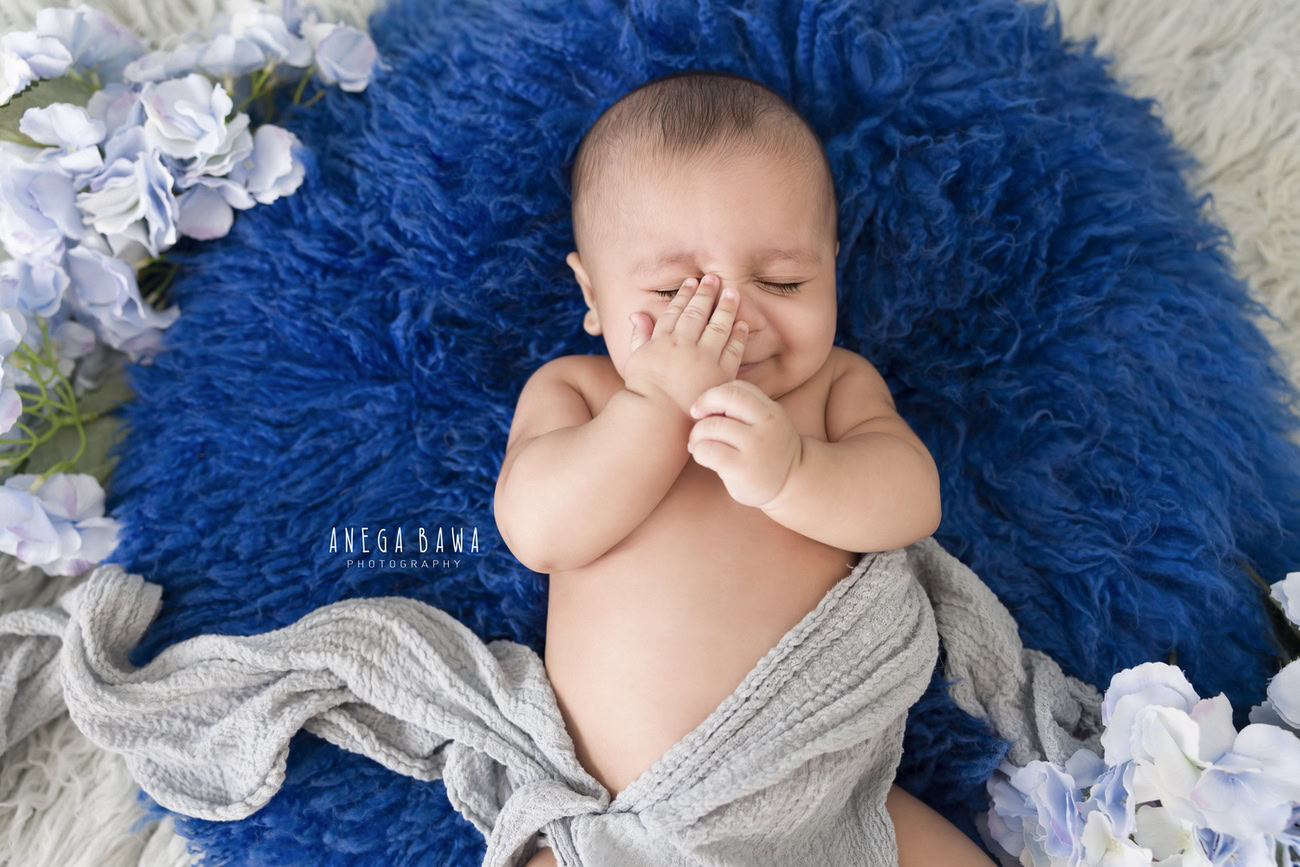 Celebrate your baby boy's milestones at 3, 4, 5, or 6 months with a charming photoshoot featuring a grey wrap, set against a vibrant royal blue rug with delicate tulips. Contact Anega Bawa for unforgettable memories in Delhi, Gurgaon, or Noida.