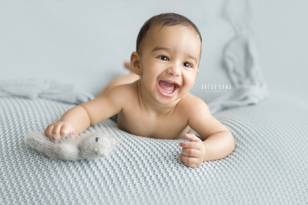 Capture the innocence of your little one with a cozy grey sheet and adorable soft toys. Book your baby boy's photoshoot with Anega Bawa in Delhi, Gurgaon, or Noida for timeless memories.