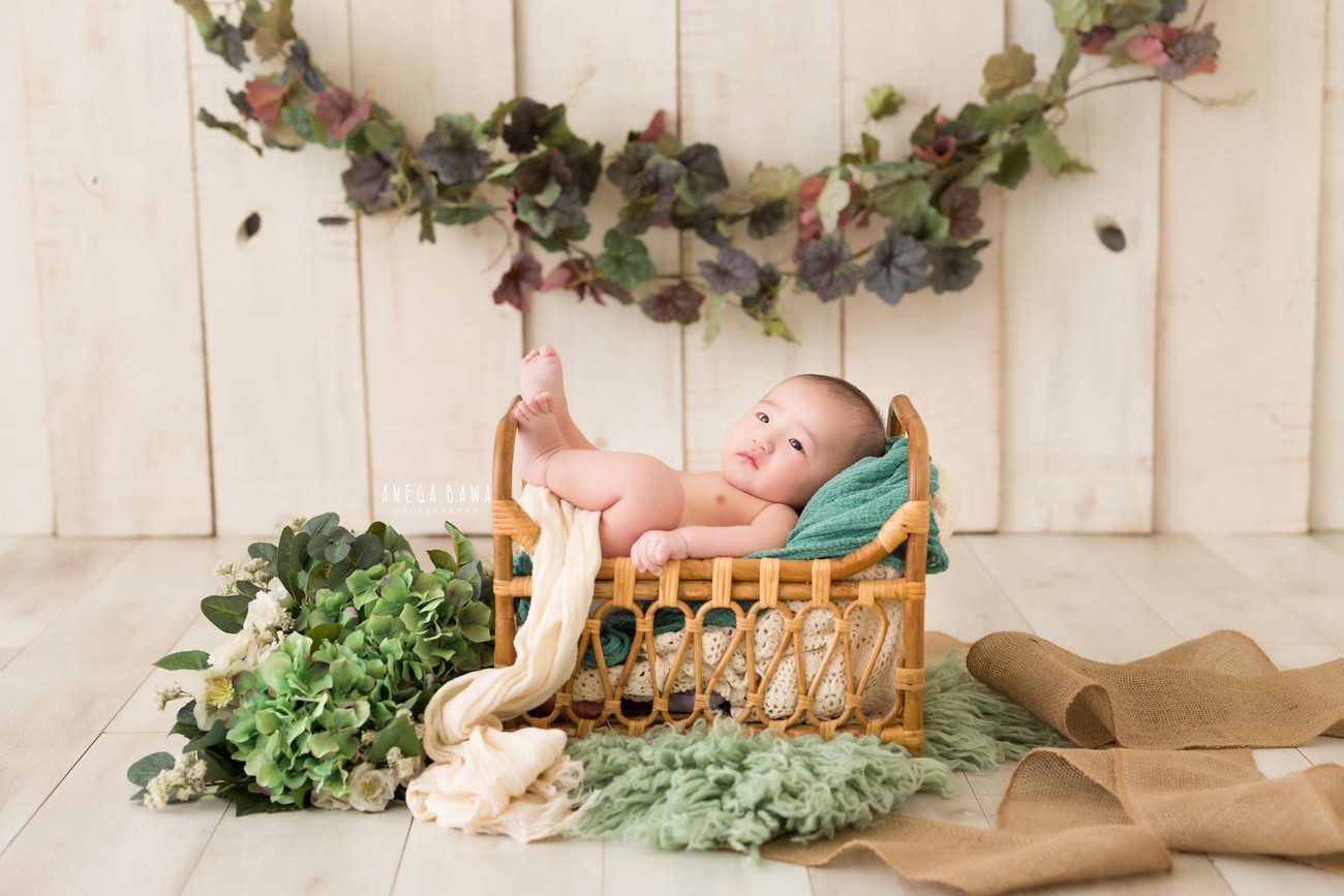 Baby boy photoshoot, 6 or 5 or 4 or 3 months, wooden cot, beige backdrop, green leafy curve. Location: Delhi, Gurgaon, Noida. Photographer: Anega Bawa.