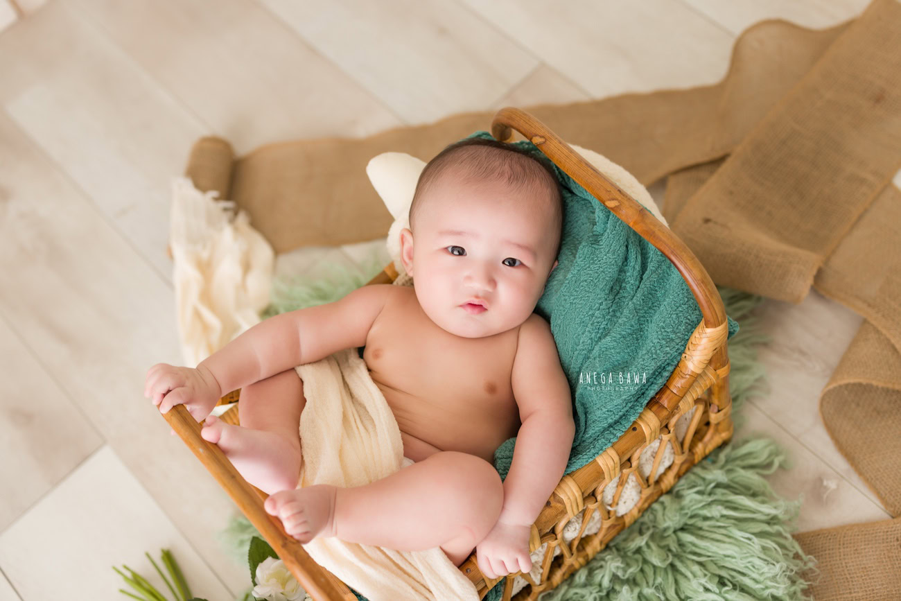Baby boy photoshoot, 6 or 5 or 4 or 3 months, wooden cot, beige sheet, beige backdrop. Location: Delhi, Gurgaon, Noida. Photographer: Anega Bawa.