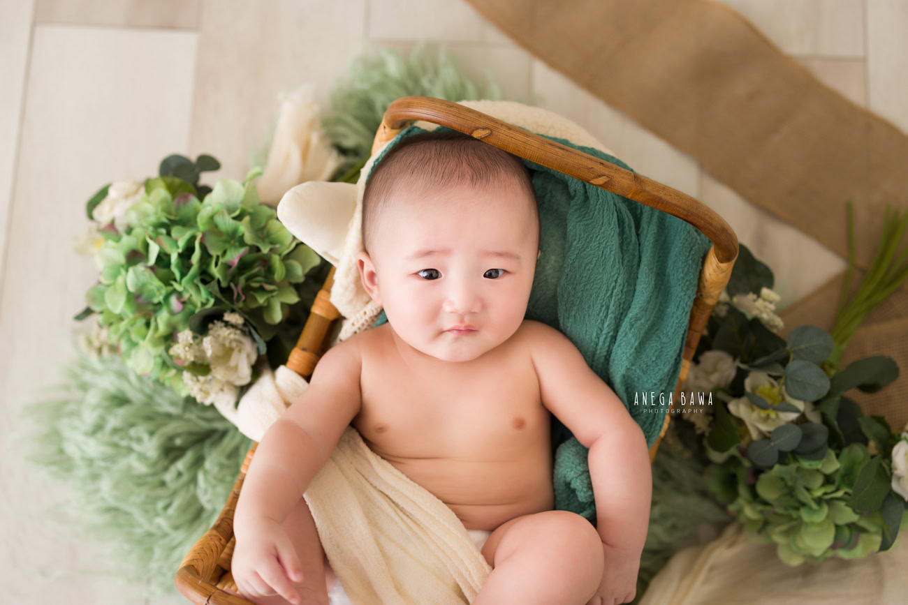 Baby boy photoshoot, 6 or 5 or 4 or 3 months, wooden cot, green rug, beige backdrop. Location: Delhi, Gurgaon, Noida. Photographer: Anega Bawa.