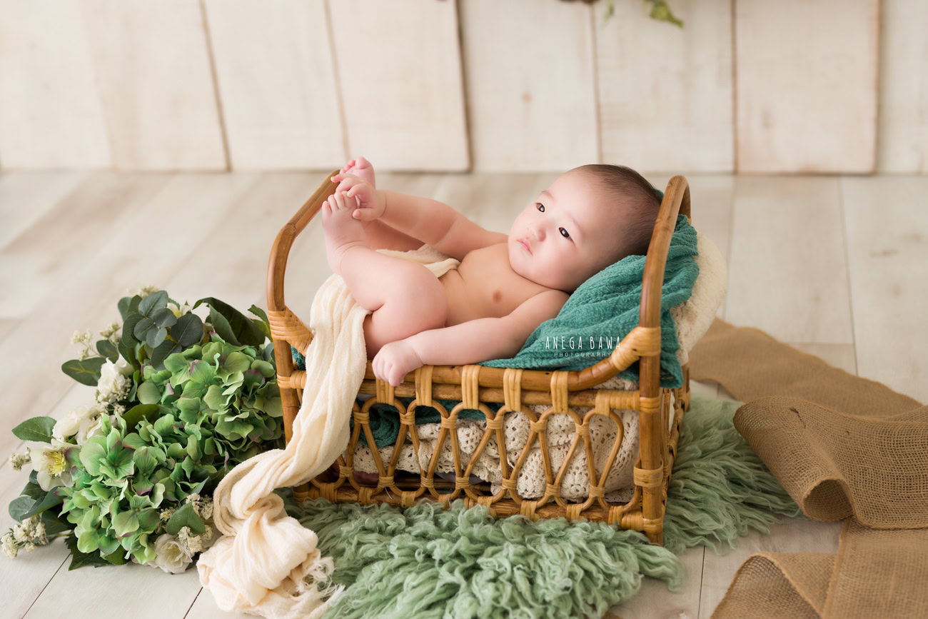 Baby boy photoshoot, 6 or 5 or 4 or 3 months, featuring a wooden cot, green rug, and beige backdrop. Location: Delhi, Gurgaon, Noida. Photographer: Anega Bawa.