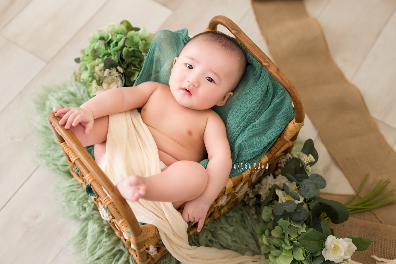 Baby boy photoshoot, 6 or 5 or 4 or 3 months, wooden cot, green rug, beige backdrop. Location: Delhi, Gurgaon, Noida. Photographer: Anega Bawa.